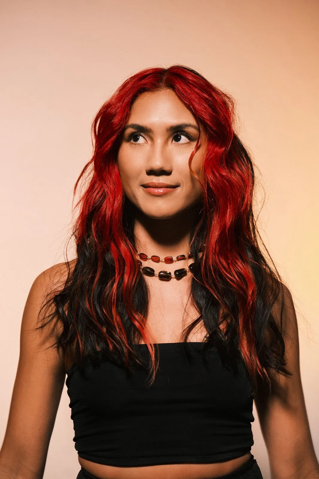 Portrait of Jasmine Sabio against a warm peach background.