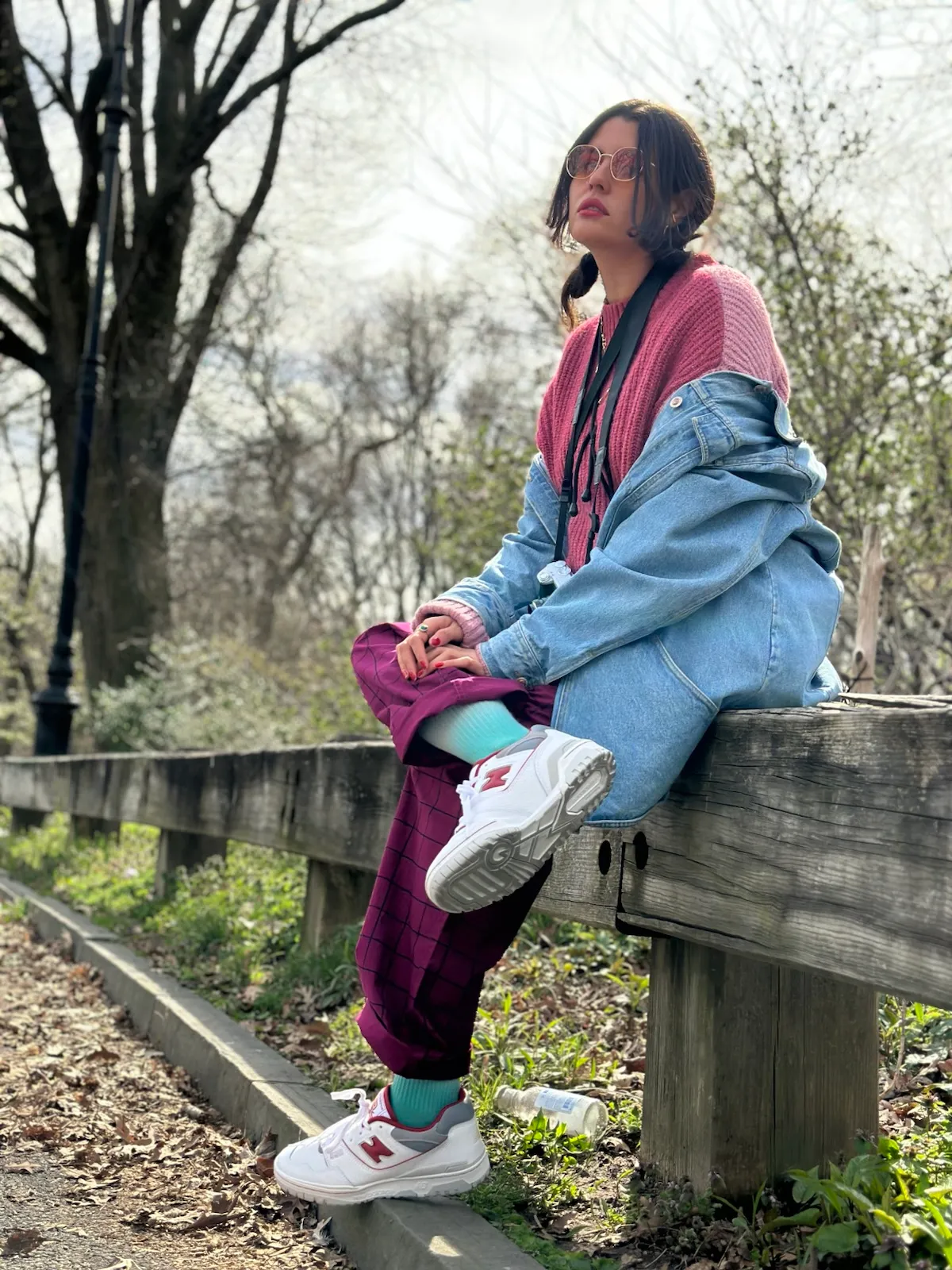 Patricia sitting on a wooden fence in a park.